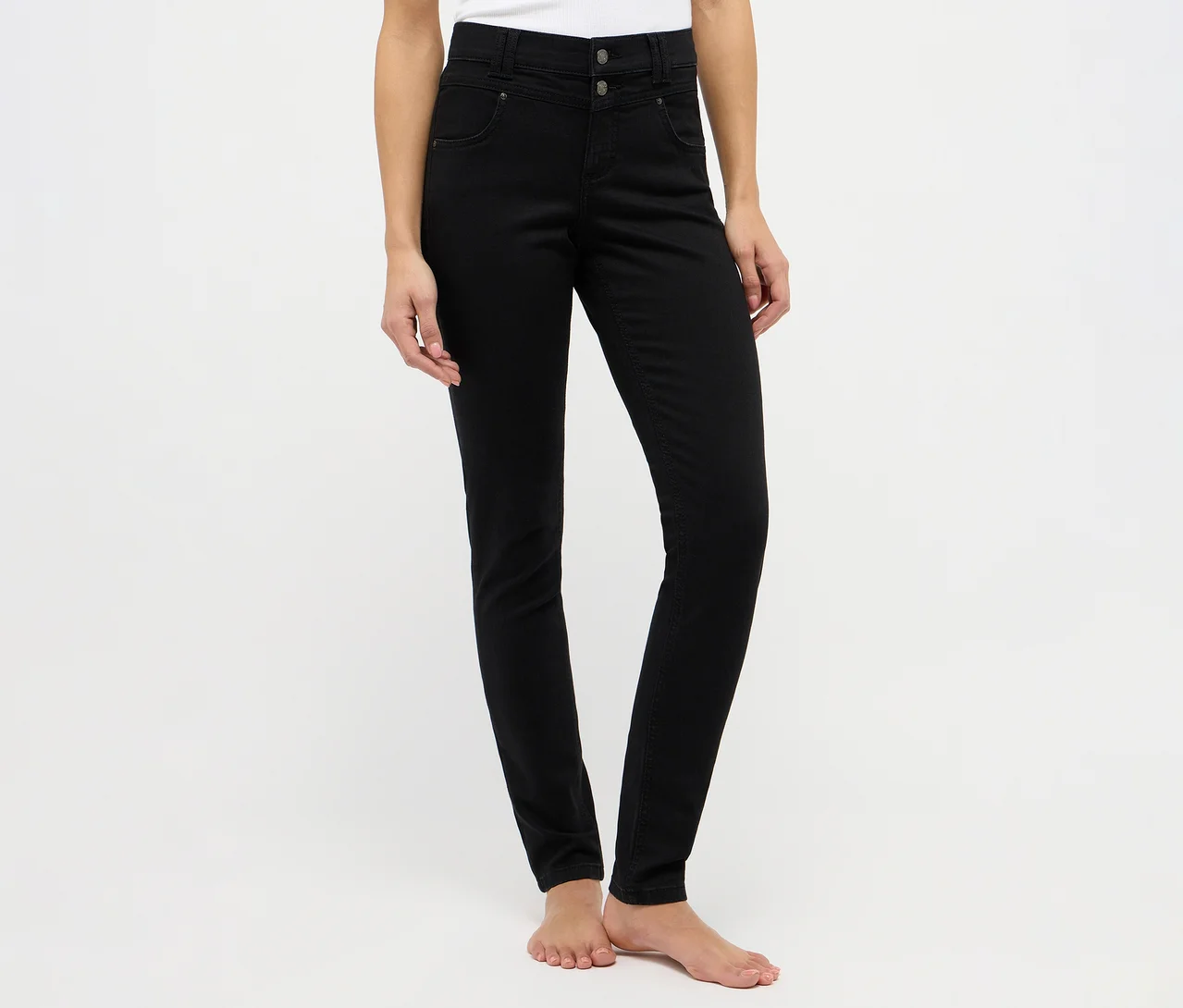 Eine Person trägt schwarze, hoch geschnittene Skinny Jeans mit zwei Knöpfen und ist barfuß.