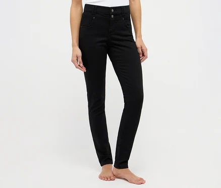 Eine Person trägt schwarze, hoch geschnittene Skinny Jeans mit zwei Knöpfen und ist barfuß.