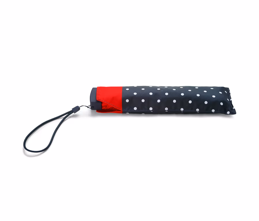 Ein Taschenschirm mit einem schwarzen Bezug mit weißen Punkten und einem roten Streifen.