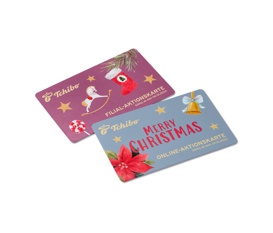 Zwei Tchibo Karten mit weihnachtlichen Motiven. Eine lilafarbene Karte zeigt ein Schaukelpferd und einen roten Strumpf, die andere blaue Karte zeigt die Nachricht Frohe Weihnachten.