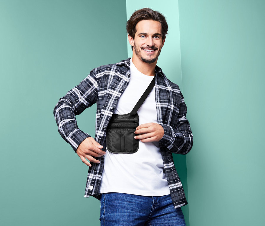 Lächelnder Mann posiert mit schwarzer Sicherheitstasche mit Schultergurt.