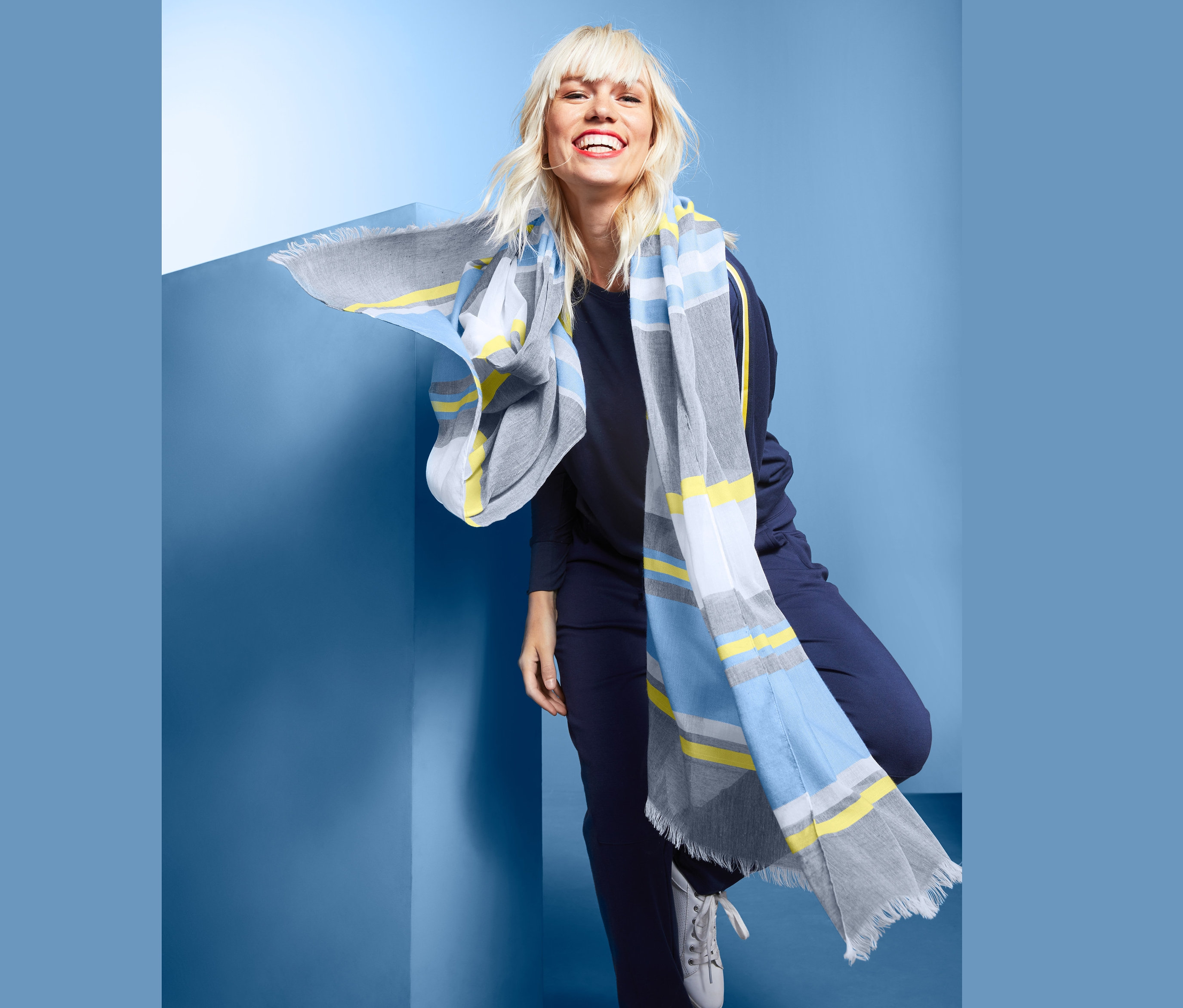 Frau mit blonden Haaren lächelt und posiert mit XL-Schal.
