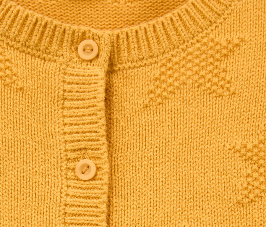 Detailansicht einer gelben Strickjacke aus Bio-Baumwolle mit Knöpfen.
