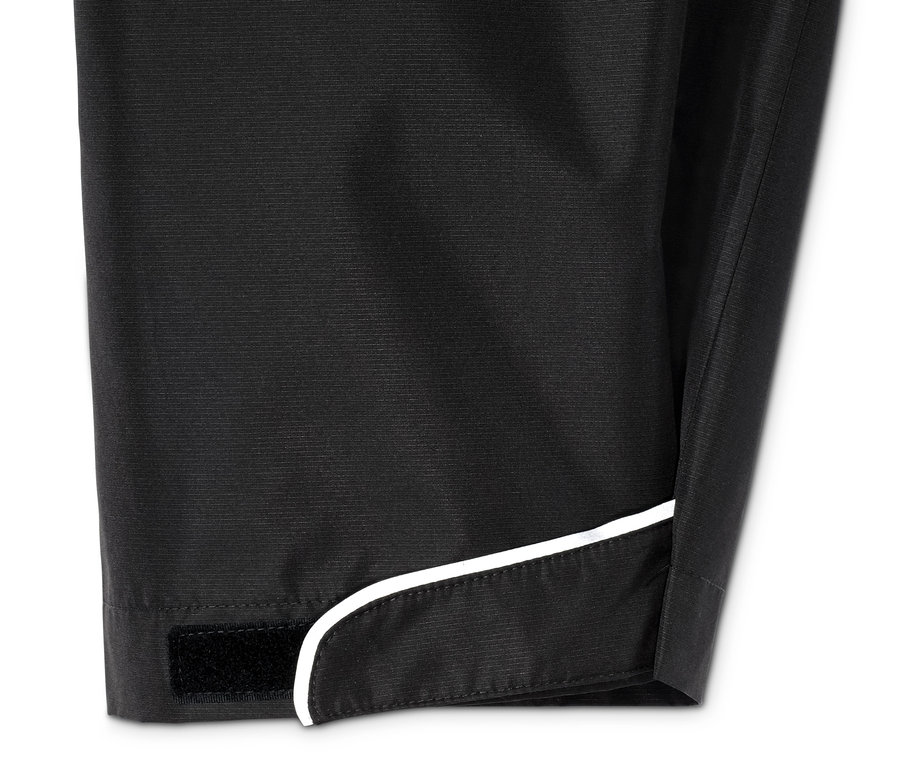 Detailaufnahme einer schwarzen Regenhose mit weißer Borte und Klettverschluss.