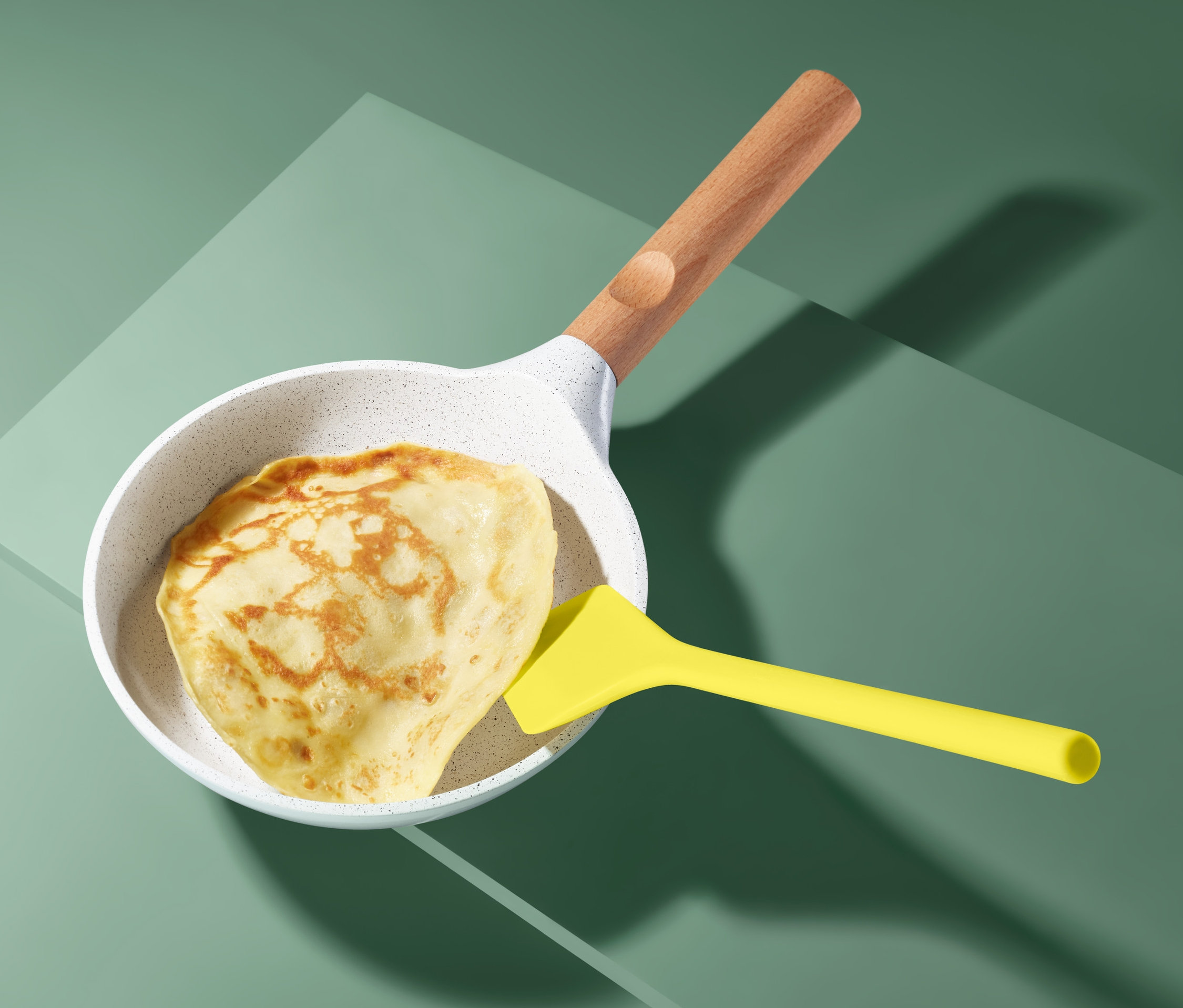 Ein Eierkuchen in einer Pfanne mit einem Eier- und Pfannkuchenwender.