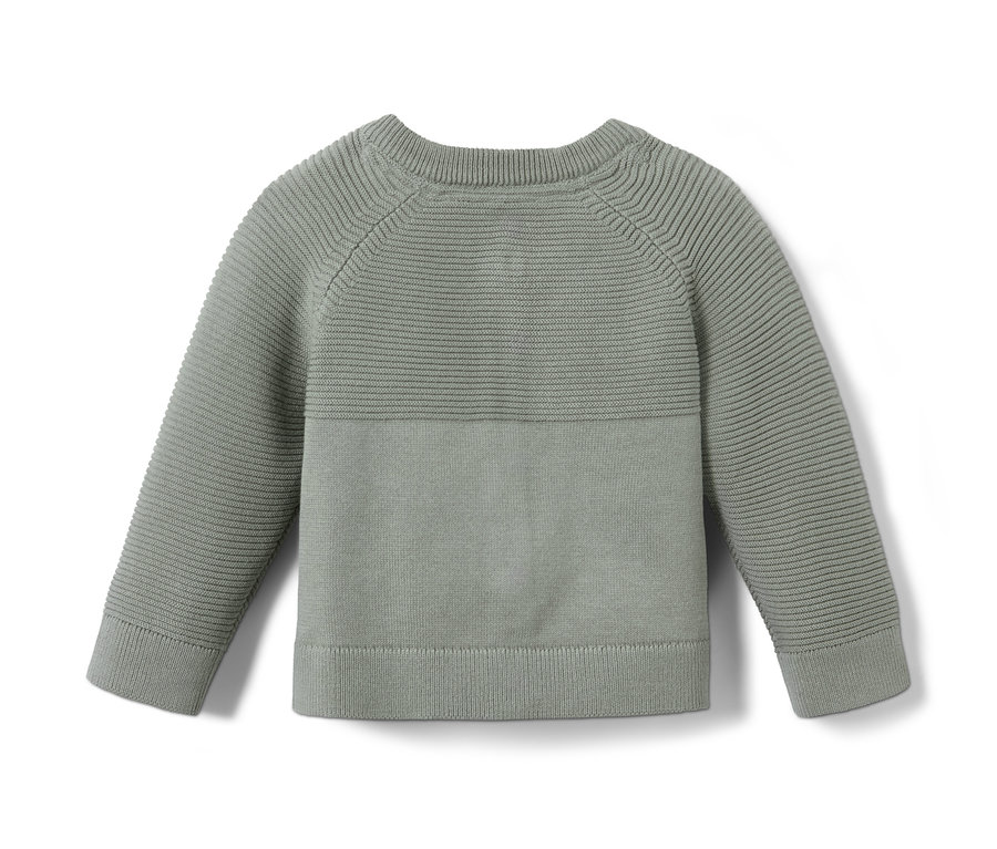 Eine grüne Strickjacke liegt auf einem weißen Hintergrund.