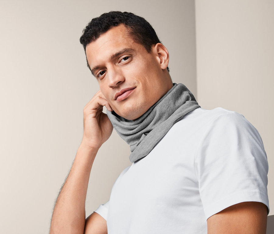 Mann trägt ein Multifunktionstuch um den Hals und hält es an sein Ohr.