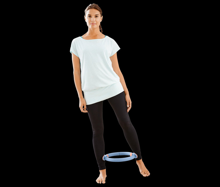 Frau trainiert mit Pilatesring zwischen ihren Beinen.