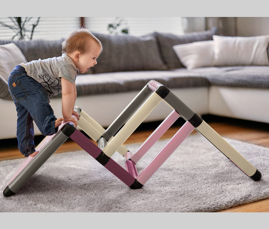 Ein Kind klettert auf ein farbenfrohes Quadro-Home-BEGINNER-Set auf einem Teppich.