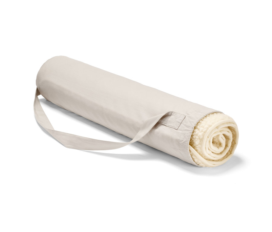 Eine zusammengerollte Schurwoll-Yogamatte in einer beigen Tragetasche mit Gurt.