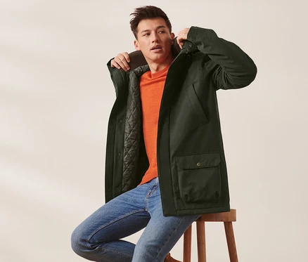 Mann sitzt auf Hocker und trägt Jacke.