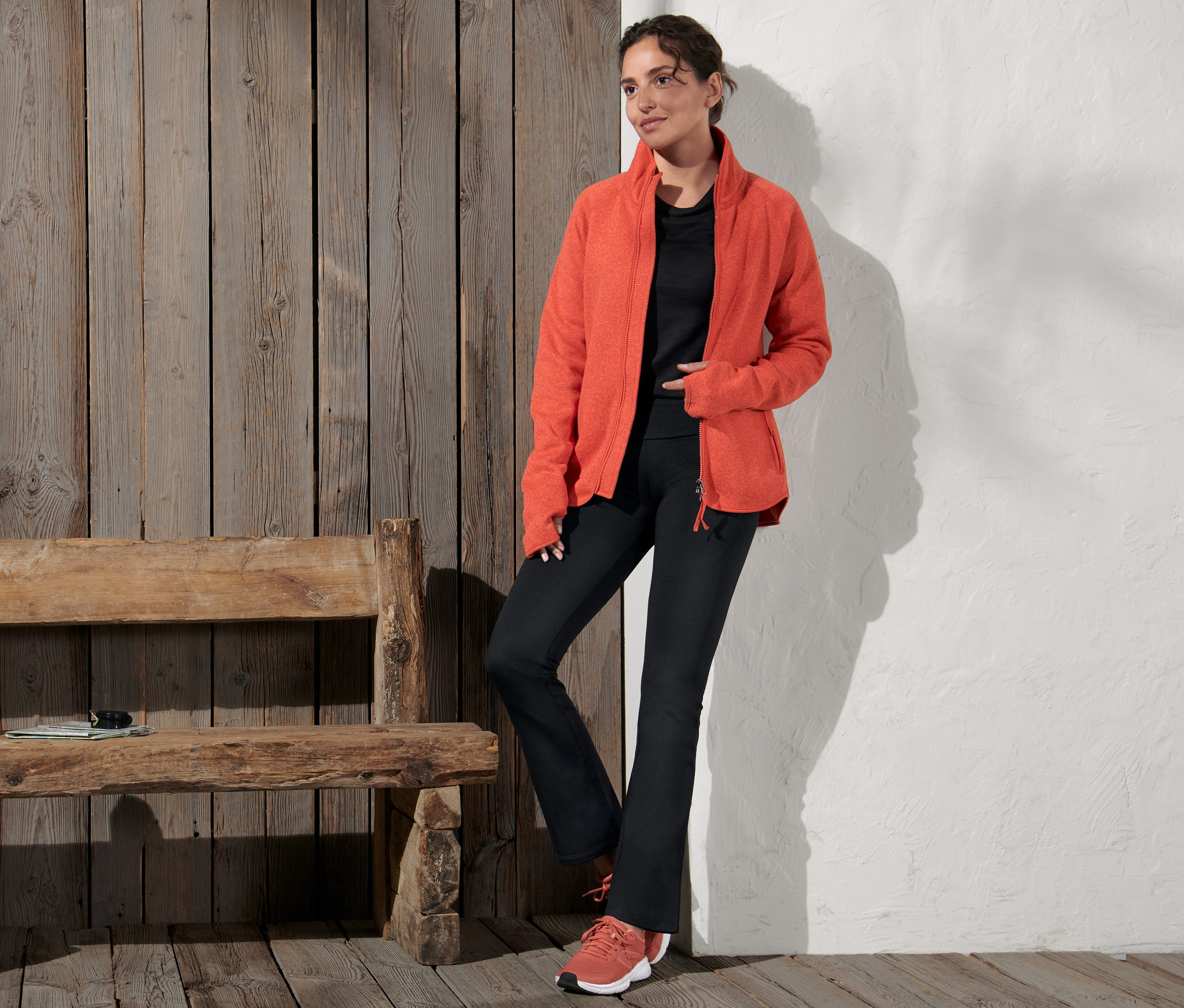 Frau posiert in orangefarbener Jacke und Thermo-Jazzpants.