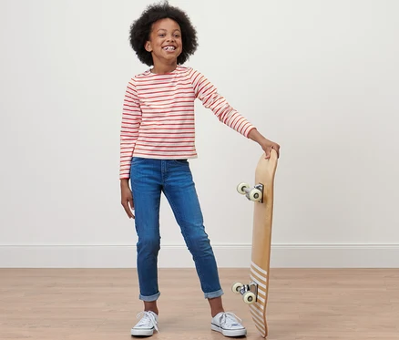 Mädchen posiert mit Skateboard und trägt ein Kinder-Cropped-Shirt.