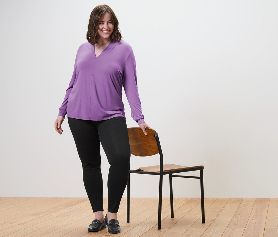 Frau posiert in Blusenshirt mit V-Ausschnitt und Jeggings.