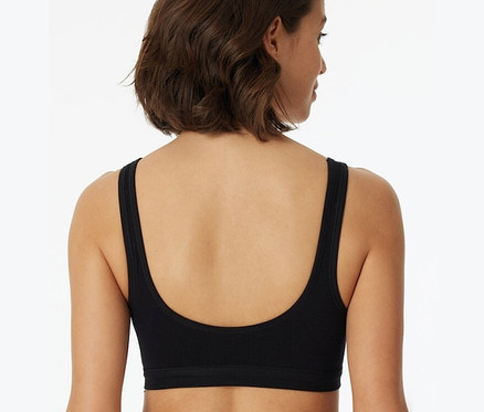 Rückansicht einer Frau mit kurzem braunem Haar, die einen schwarzen SCHIESSER Bustier mit Cups und Bio-Baumwolle trägt.