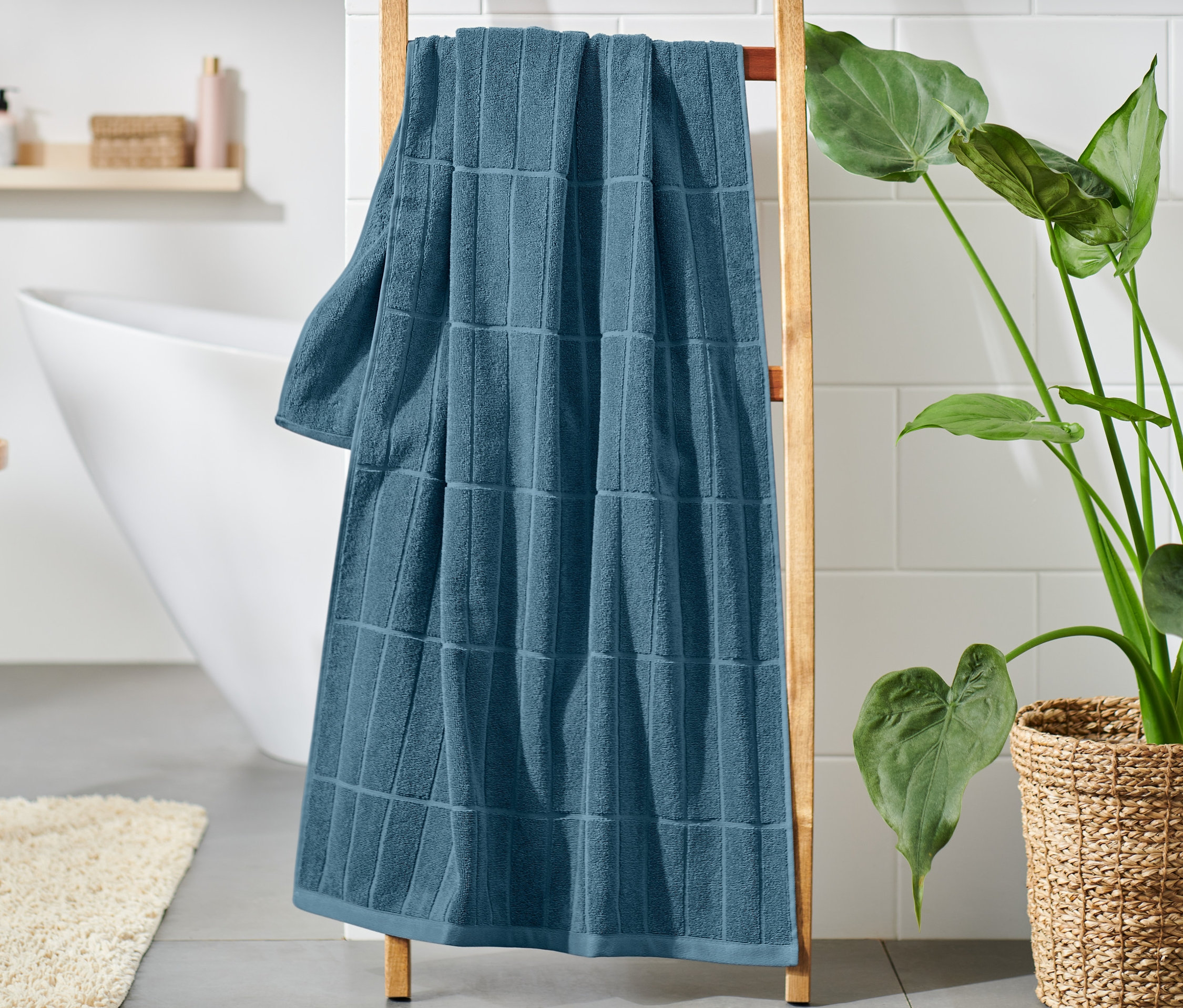 Blaues Premium-Badetuch hängt im Badezimmer auf einer Holzleiter.