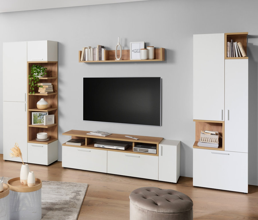 Wohnzimmer mit einer Frau, die auf einem beige Sofa sitzt und fernsieht. An der Wand hängt ein eichenfarbenes Wandboard »Nonza«.
