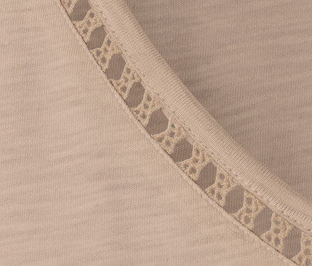 Detailansicht eines beigen Shirts mit Crochet-Tape am Ausschnitt.