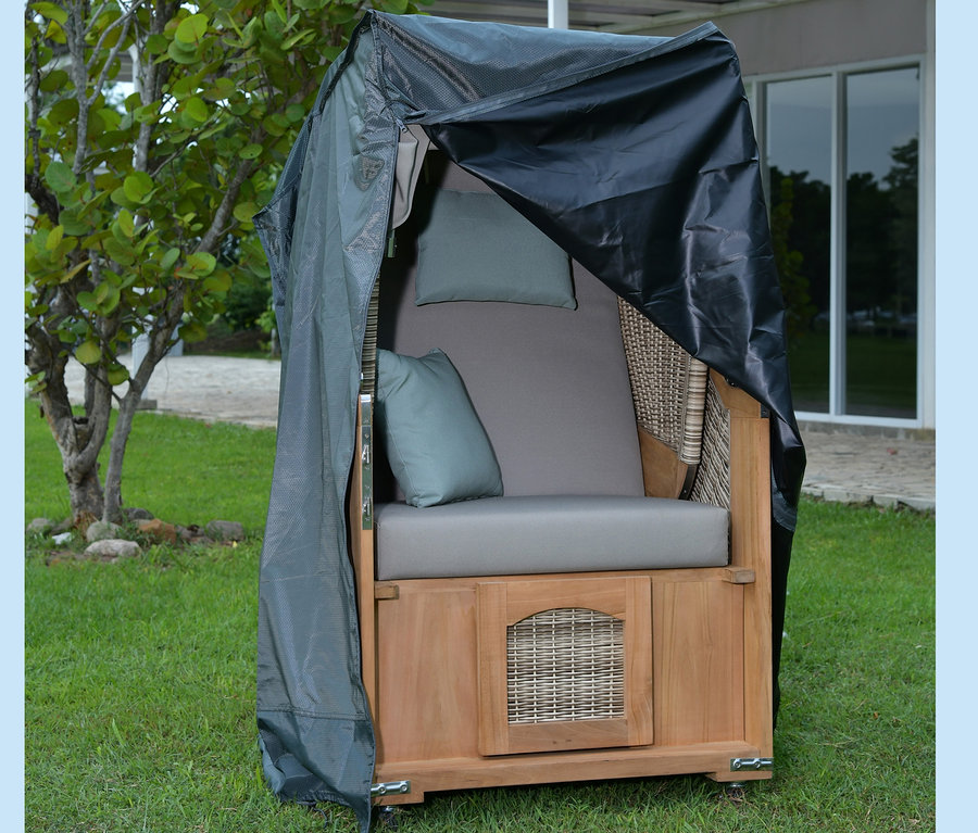 deVries Teak-Strandkorb, 1-Sitzer mit grauen Kissen und schwarzer Abdeckung steht auf einer Wiese.