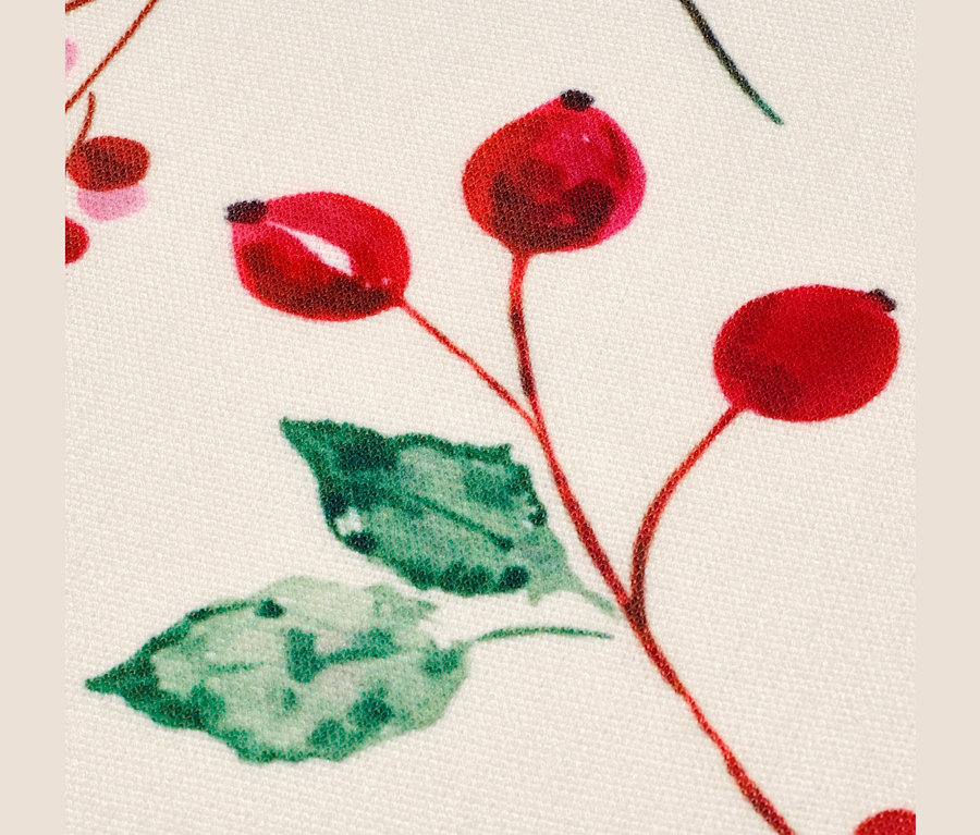 Detailaufnahme eines Stoffes mit einem Muster aus roten Beeren und grünen Blättern. 4 Wende-Platzsets.