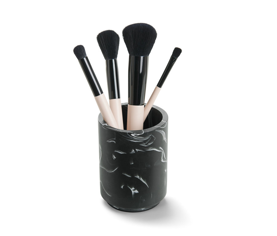 Vier Make-up-Pinsel in einem marmorierten Utensilo.