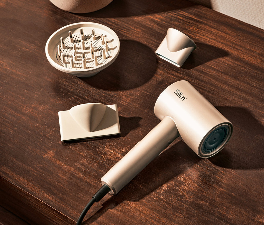 Beiger Silk'n Haartrockner SilkyAir Pro mit Zubehör auf braunem Holztisch.