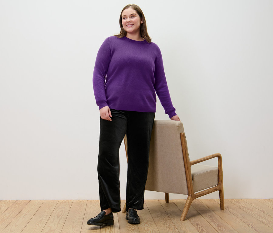 Frau posiert in lila Feinstrickpullover mit Cashmere und schwarzer Samt-Palazzohose.