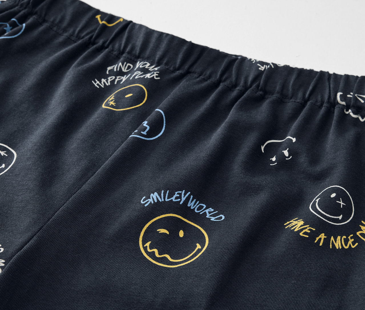 Detailaufnahme einer Kinder-Pyjama SMILEYWORLD® mit Gesichtern und Schriftzügen.