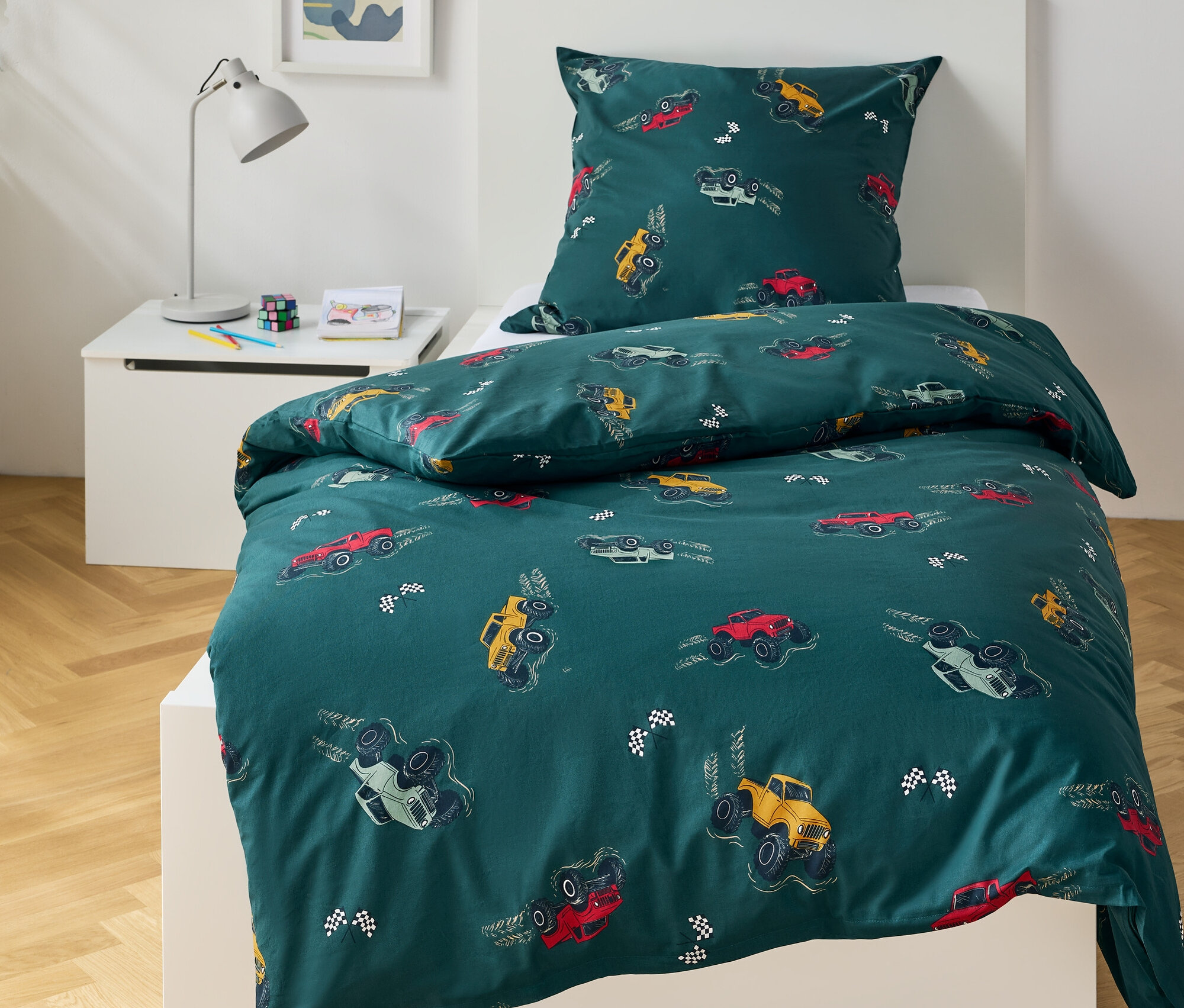 Grüne Bettwäsche mit Monster Truck-Motiv auf einem Bett.