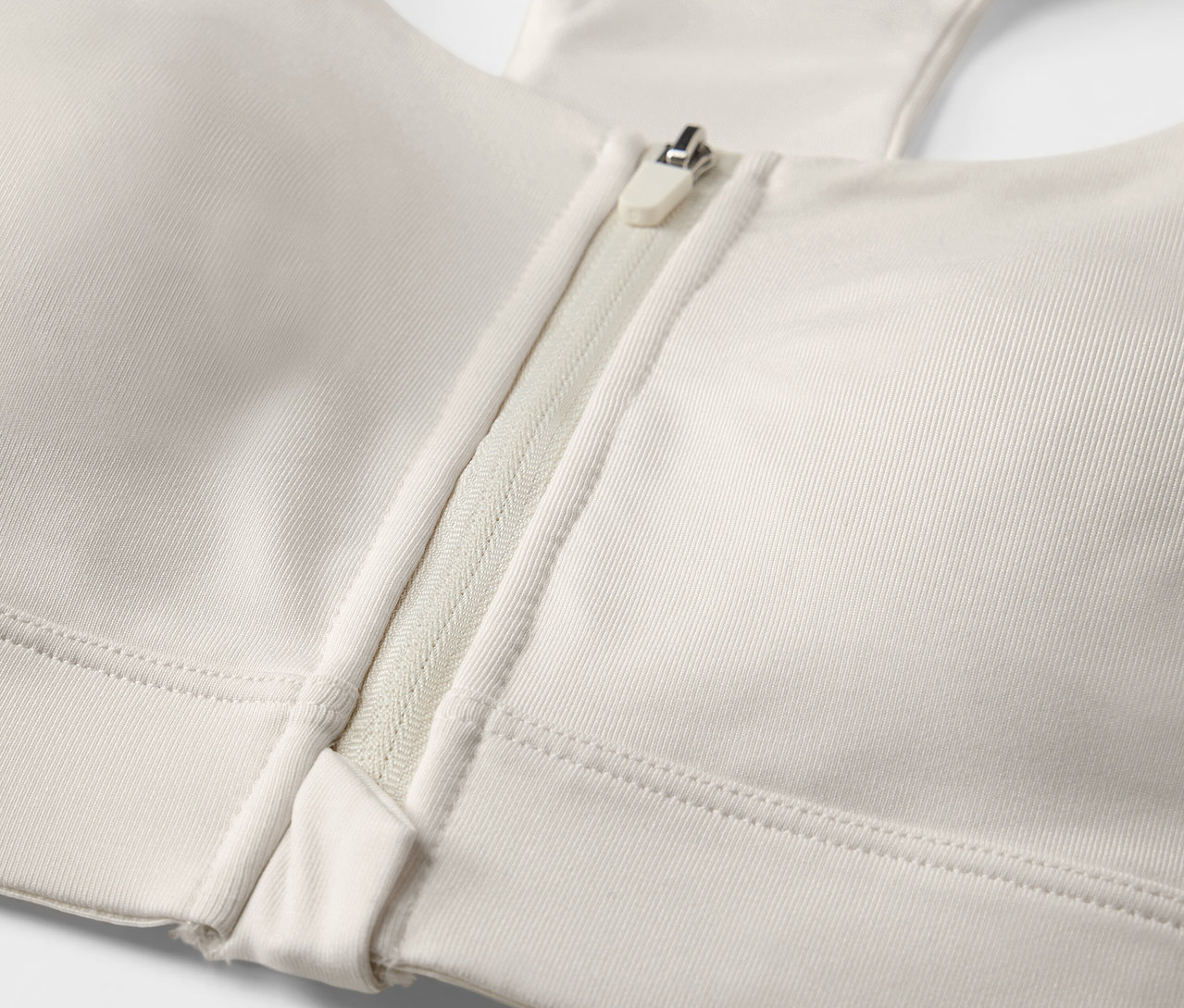 Detailaufnahme von einem offwhite Sport-BH mit Frontreißverschluss.