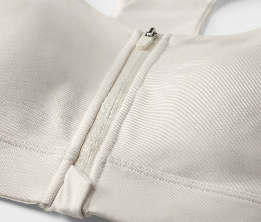 Detailaufnahme von einem offwhite Sport-BH mit Frontreißverschluss.