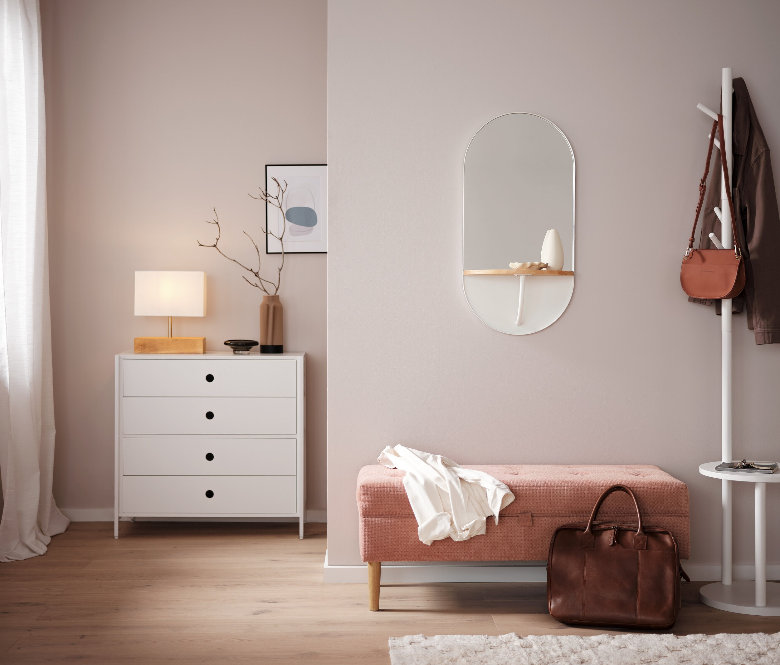 Schlafzimmer mit weißer Kommode, Spiegel und rosa Bank.