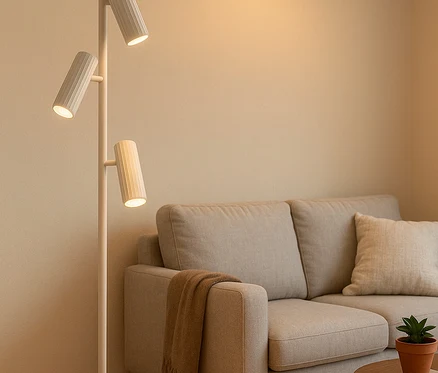 Wohnzimmer mit beigem Sofa, Couchtisch aus Holz und einer weißen Stehlampe mit drei Leuchten.