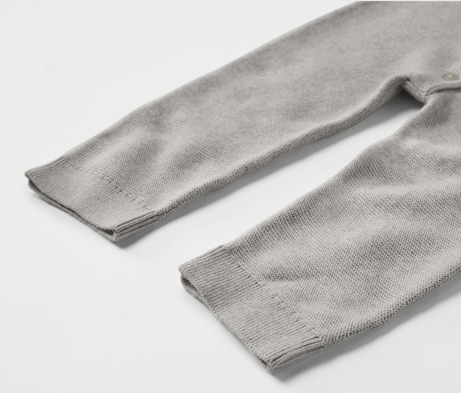 Detailansicht eines grauen Baby-Strickoveralls.