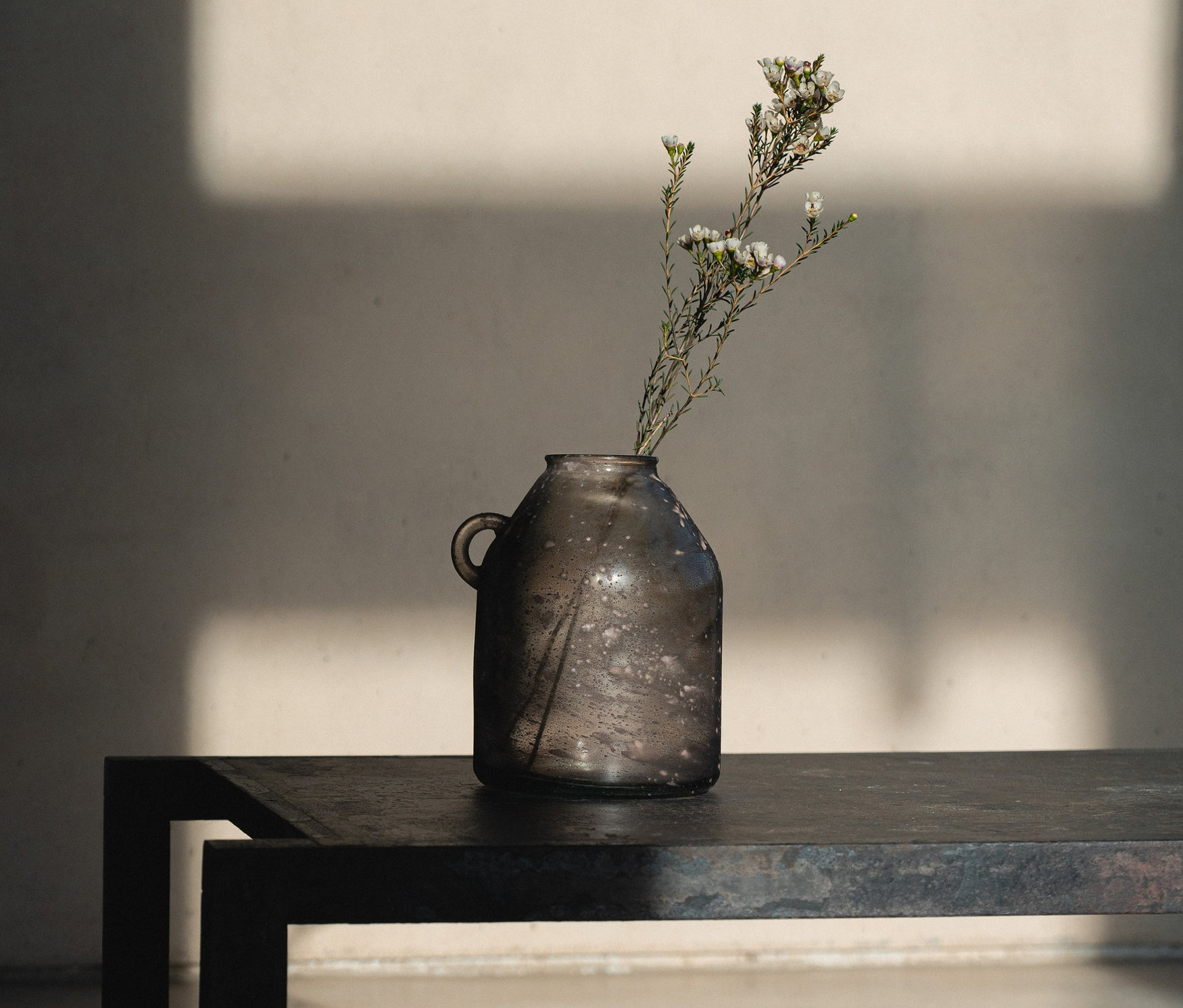 Eine Vase mit blühenden Zweigen steht auf einem Tisch.