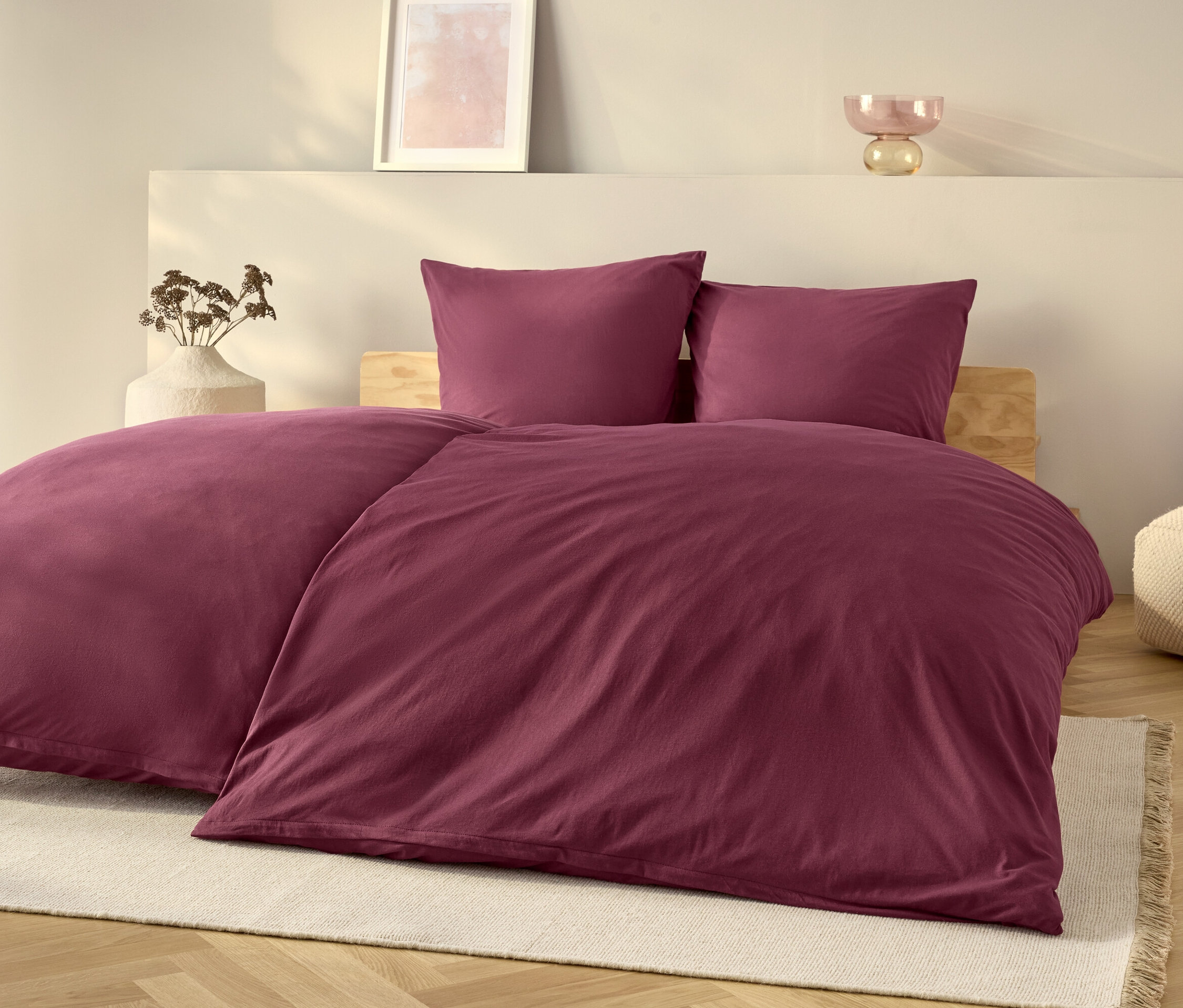 Ein lila Bettwäsche-Set auf einem Bett mit einem weißen Teppich.