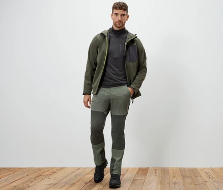 Mann steht und trägt eine grüne Outdoorhose.