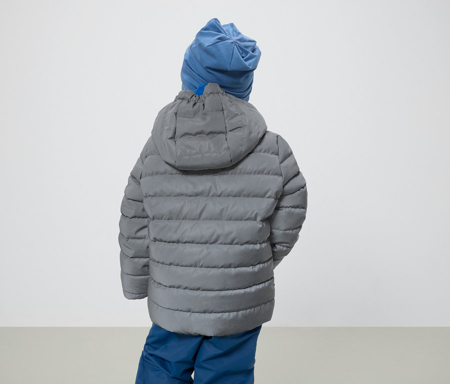 Junge mit dem Rücken zur Kamera trägt eine graue Jacke mit Kapuze und eine blaue Mütze.