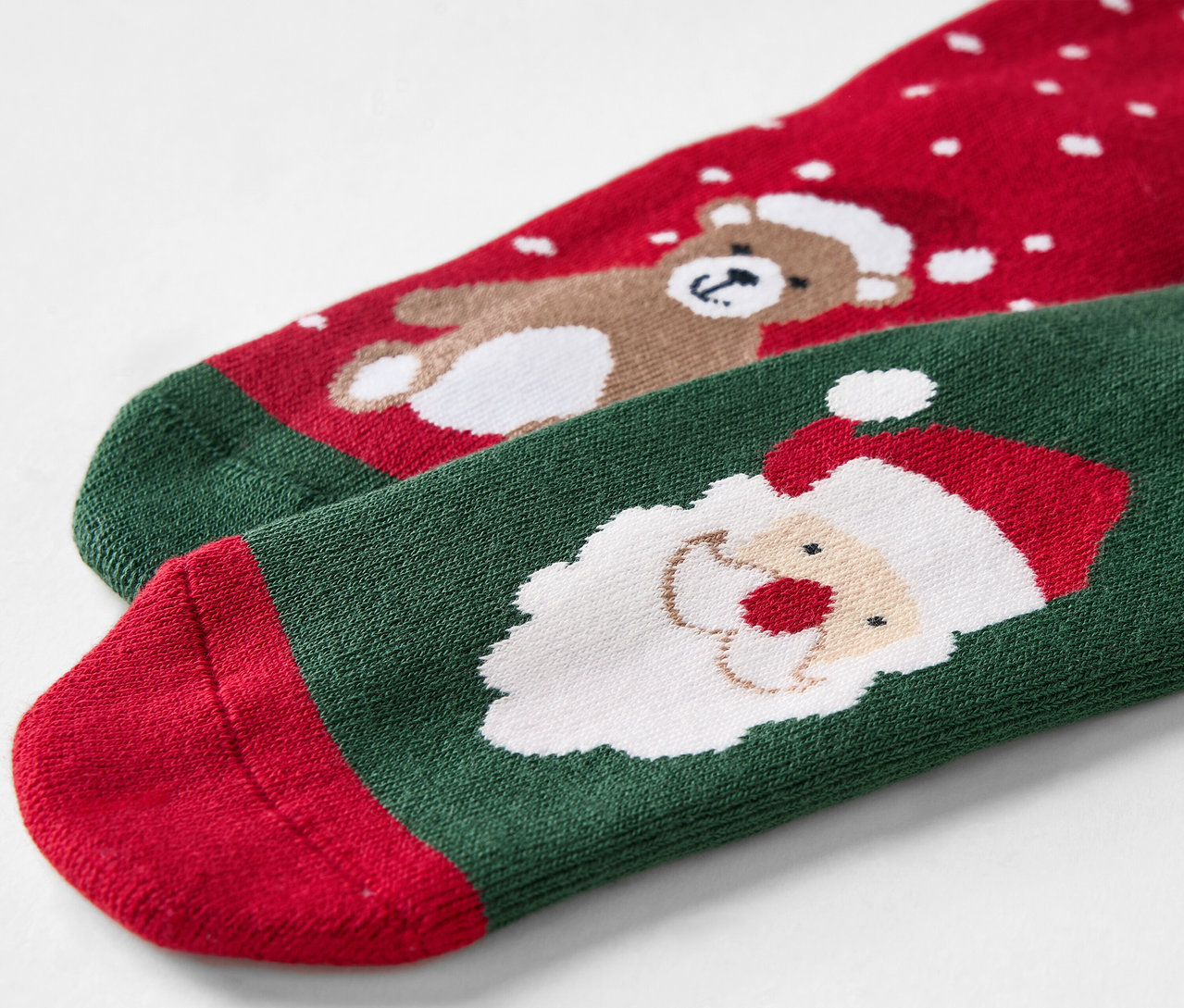 Detailaufnahme von roten und grünen Weihnachtssocken mit Bär und Weihnachtsmann.