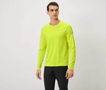 Mann posiert in neongelbem Langarmshirt und schwarzer Trainingshose.