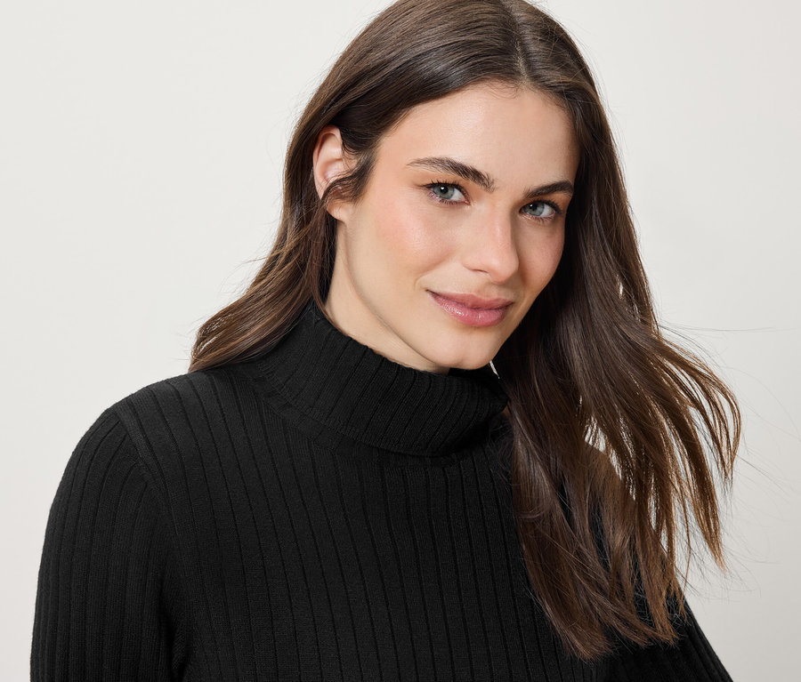 Porträt einer lächelnden Frau mit langen braunen Haaren in einem schwarzen Rollkragenpullover.
