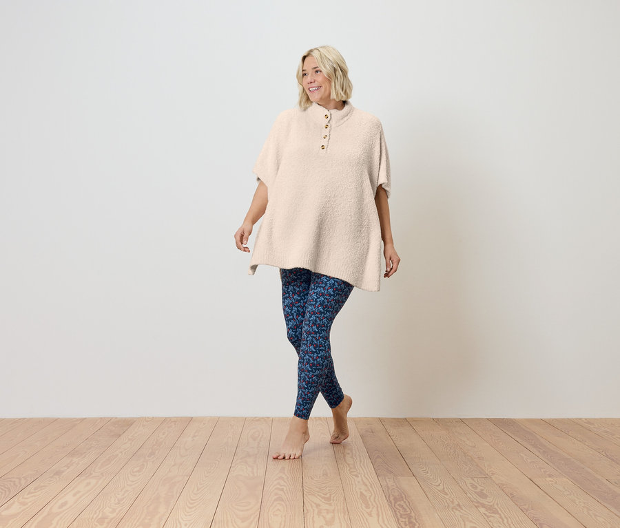 Frau geht barfuß auf Holzboden und trägt eine kurzärmlige, cremefarbene Tunika und blaue Leggings.