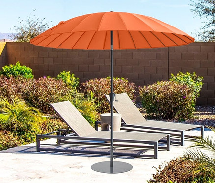 Ein orangefarbener Leco Shanghai Sonnenschirm mit einem Durchmesser von 270 cm steht hinter zwei Liegestühlen am Pool.