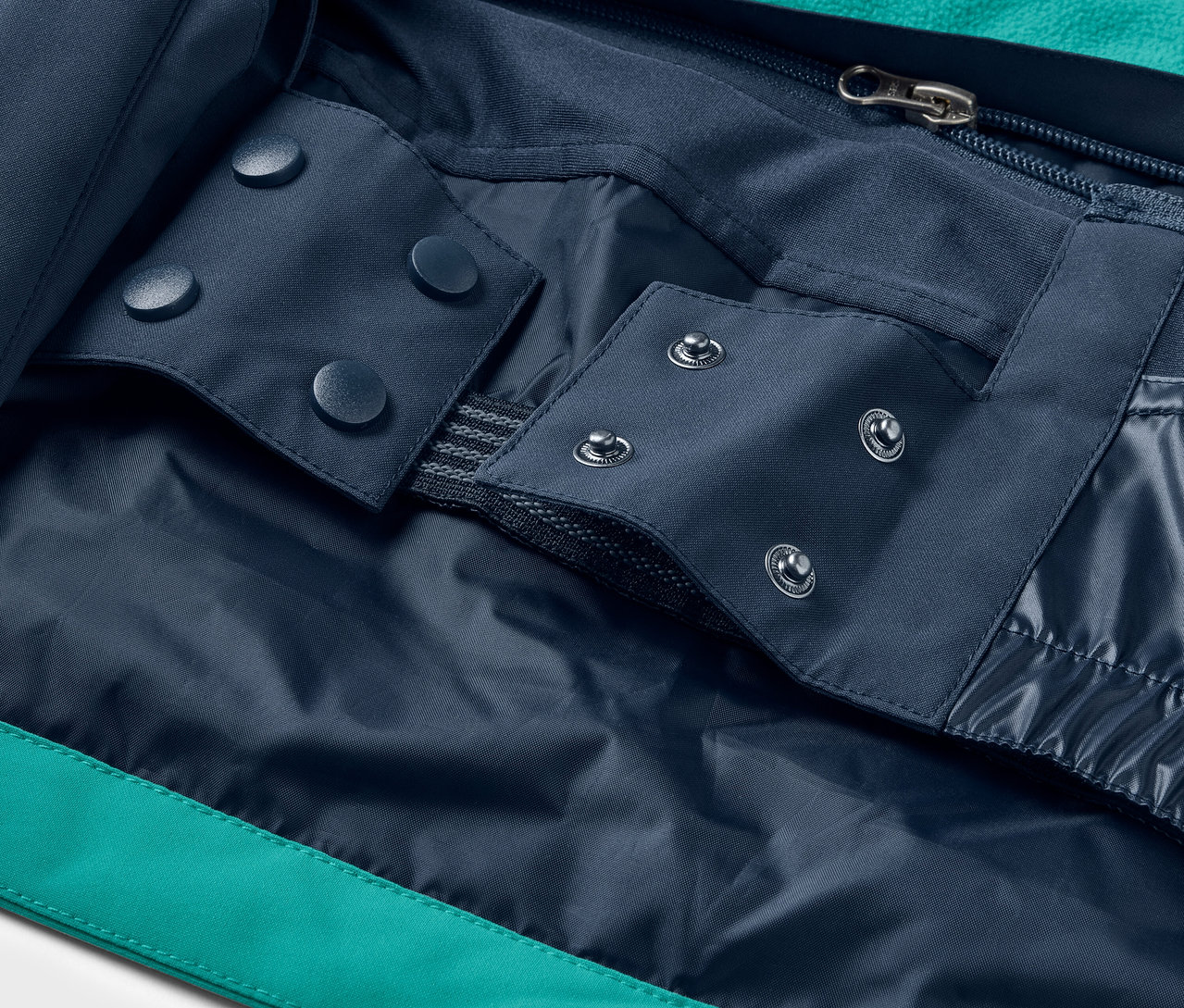 Detail einer Jacke mit blauen Druckknöpfen und Reißverschluss.