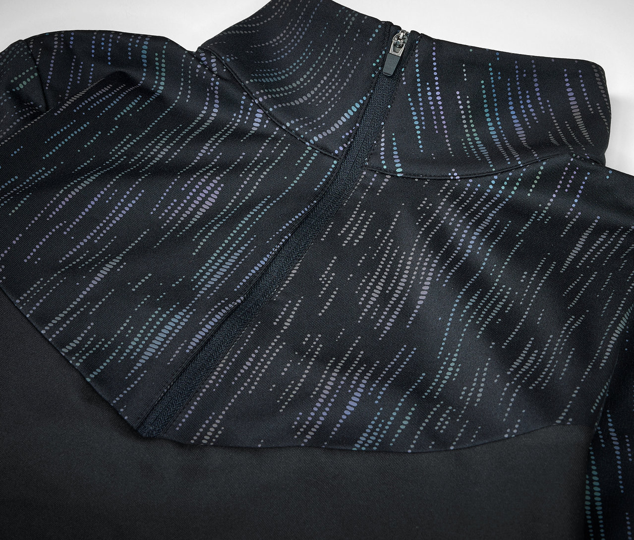 Detailaufnahme eines schwarzen Sportoberteils mit Reißverschluss und Muster.