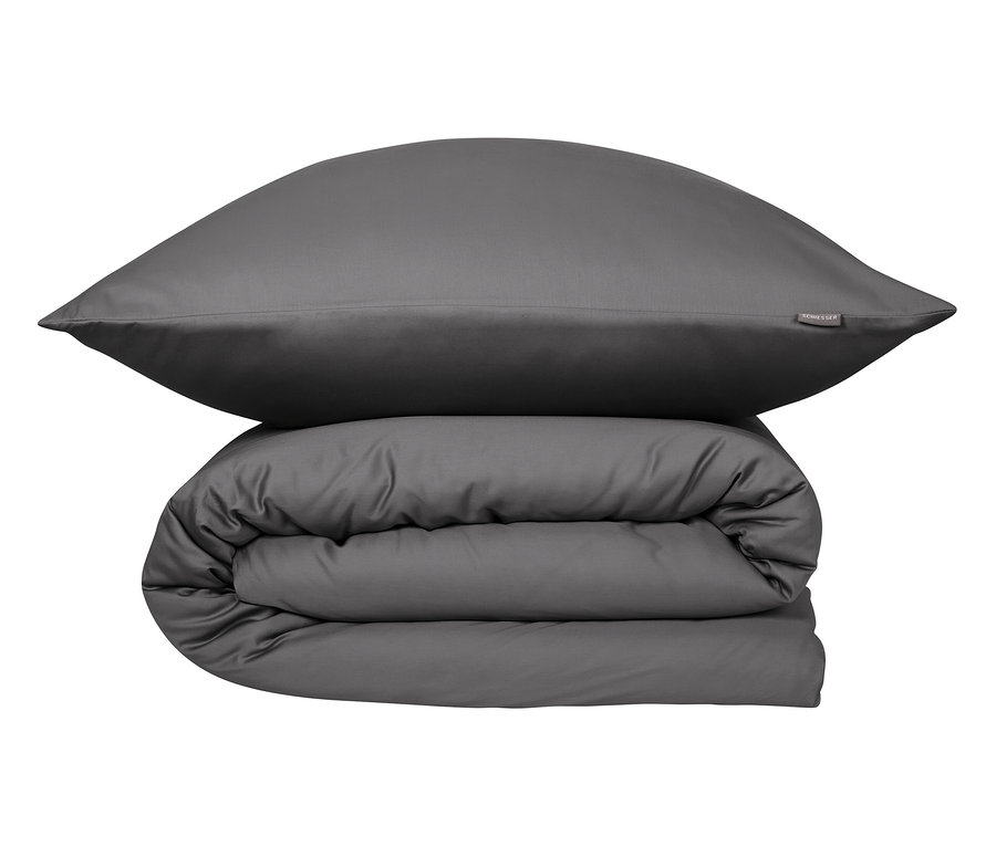 Ein graues Kissen liegt auf einer gefalteten, grauen Bettdecke.