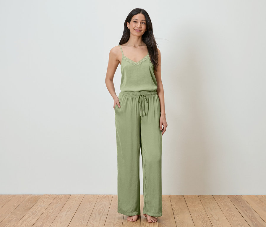 Frau steht mit Hand in Tasche und trägt ein grünes zweiteiliges Loungewear-Set.