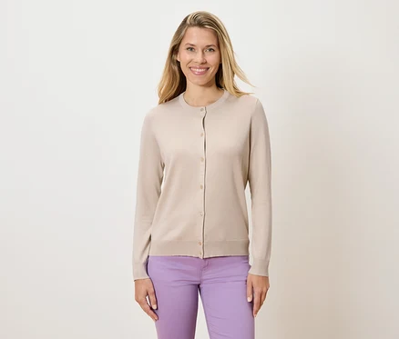 Frau trägt einen beigen Cardigan und lila Hosen.