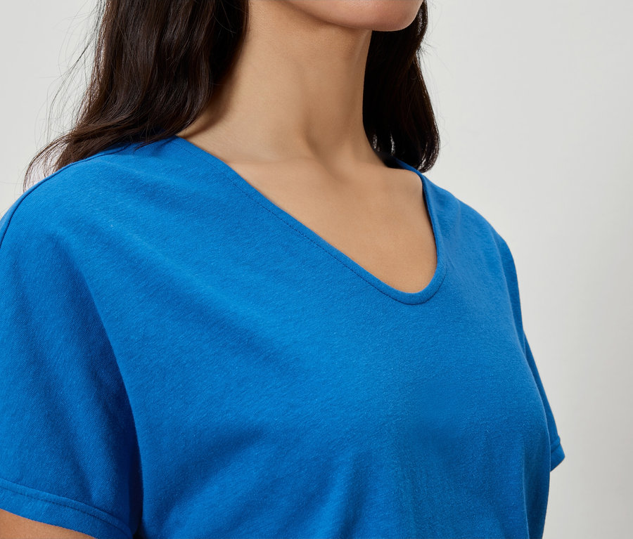 Nahaufnahme einer Frau, die ein blaues T-Shirt mit V-Ausschnitt trägt.