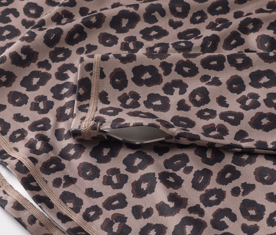 Nahaufnahme eines Sportoberteils mit Leopardenmuster und einer Tasche am Ärmel.